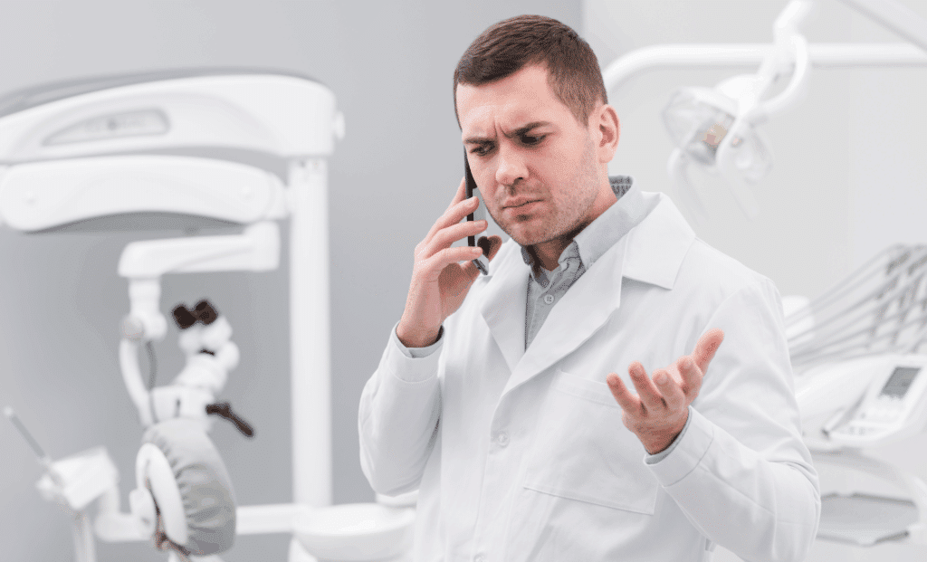 Stressed dentist on phone representing challenges of the dental workforce shortage.